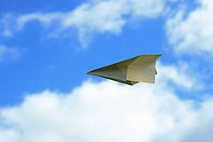 Symbolbild Pressemitteilung: Papierflieger vor blauem Himmel